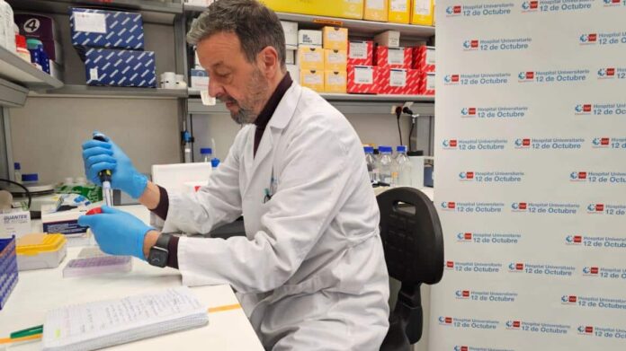 Profesional sanitario con bata blanca sentado con una pipeta en laboratorio