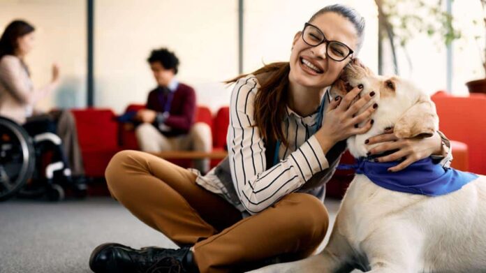 Mujer junto a perro de asistencia en una oficina