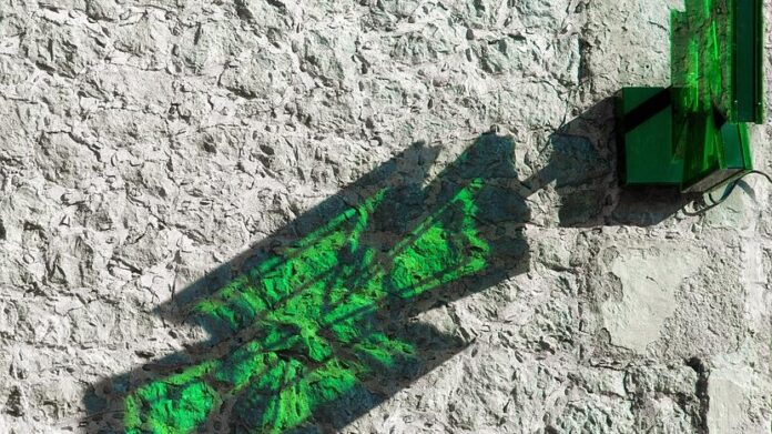 Cruz verde reflejado en pared