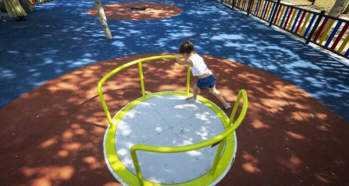 Una niña juega en la zona infantil del parque Galiana, de Usera