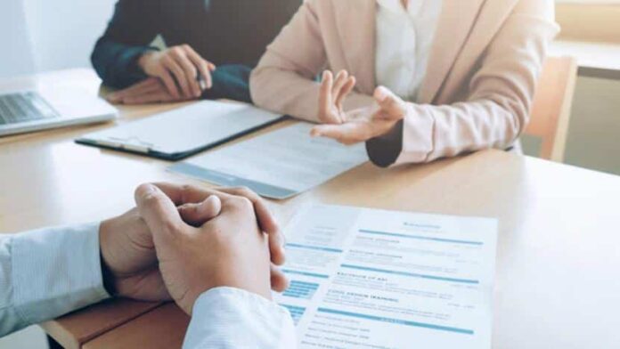 Dos personas enfrente la una de otra, con mesa entre ellos 