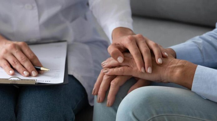 Una persona muestra su apoyo a otra colocando su mano sobre las suyas al tiempo que toma notas en una libreta