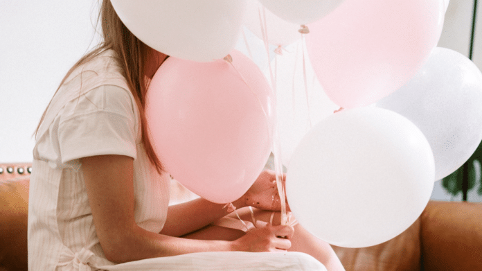 Imagen de una persona con globos rosas y blancos