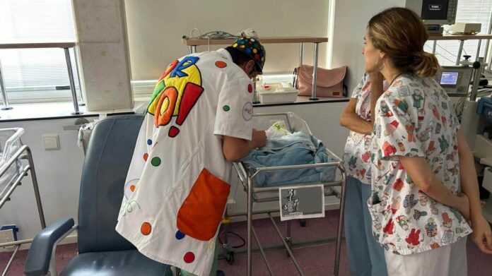 Un payaso visita a un niño en un hospital junto con enfermeras