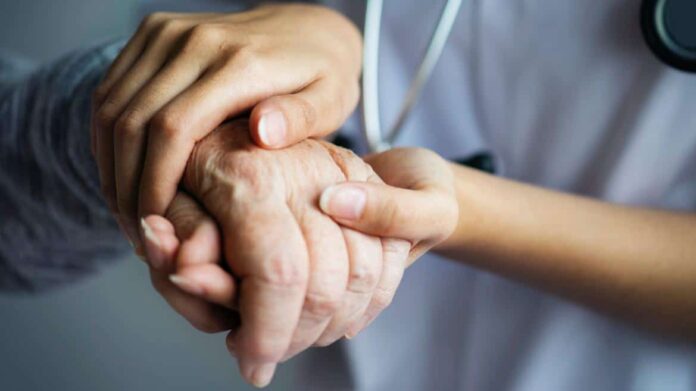 Manos de un sanitario sujetando la mano de una persona mayor