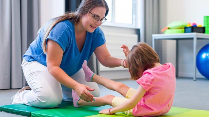 Una profesional de la fisioterapia con una alumna en un colegio