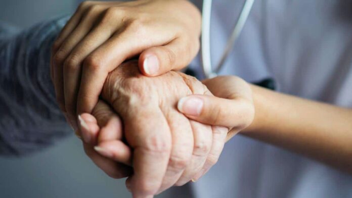 Manos de un sanitario sujetando la mano de una persona mayor