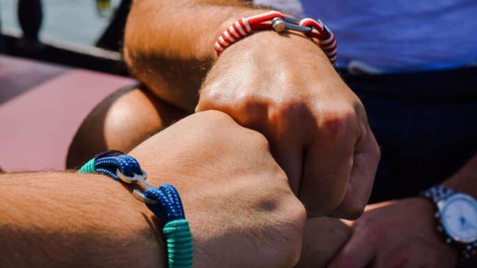 2 manos chocando los puños con pulseras de colores