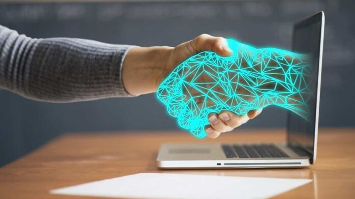 Una persona da la mano a otra digitalizada que sale de una pantalla