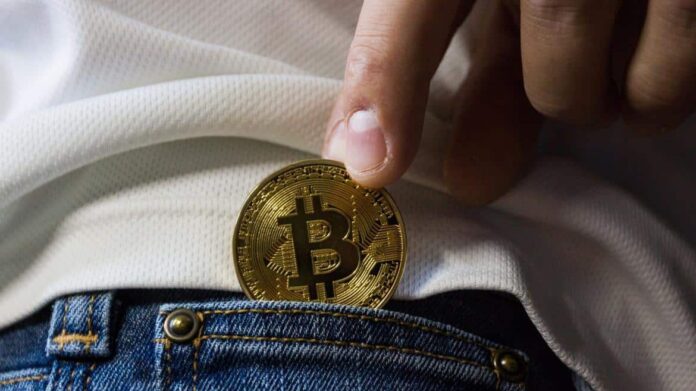 Mano metiendo una moneda a un bolsillo de pantalón