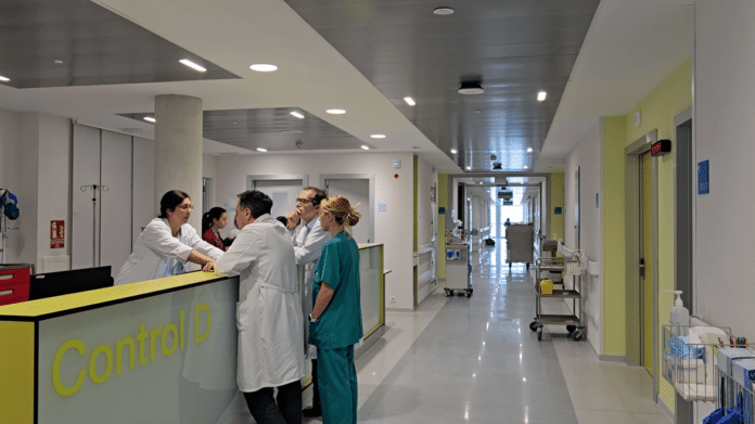 Pasillo de una planta de hospitalización con médicos hablando