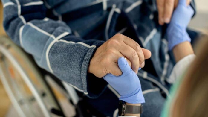 Médico sujetando la mano a paciente en silla de ruedas