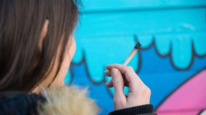 Una joven sostiene un cigarro de cannabis