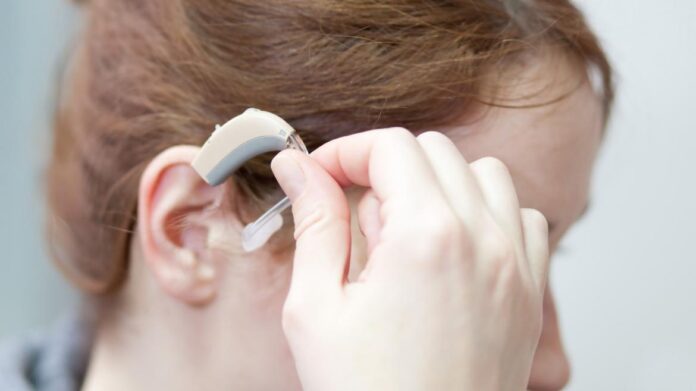 Primer plano de una mujer colocándose un audífono