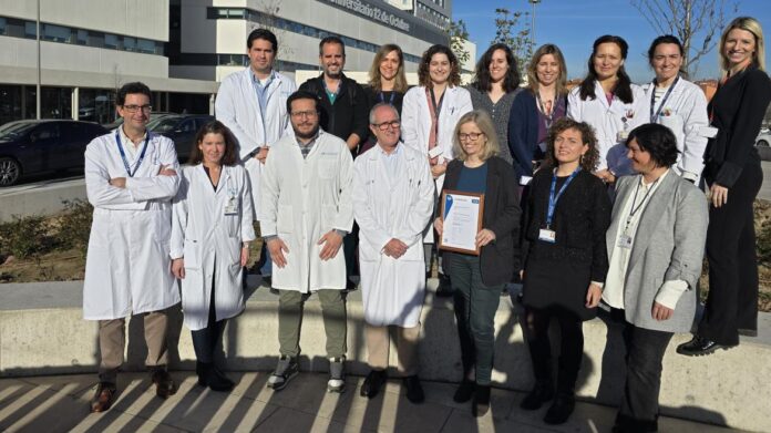 foto de grupo en exterior con batas blancas y Hospital 12 de Octubre detrás