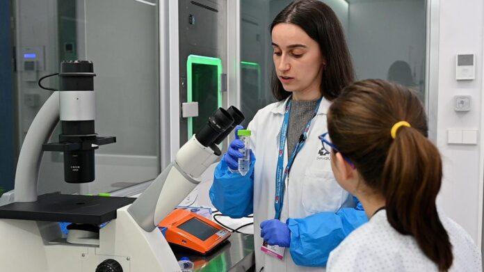 Una científica explica a una niña cómo funciona un microscopio