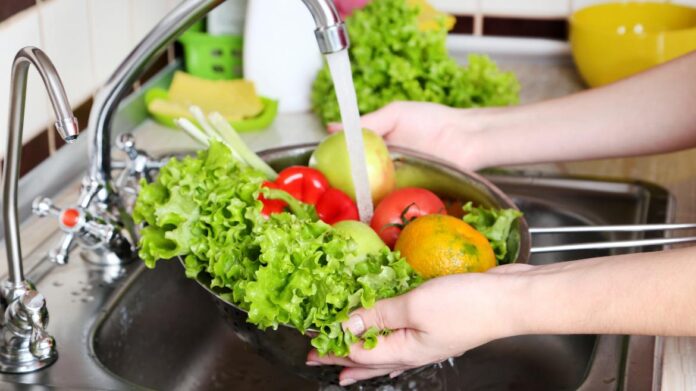 Persona lavando vegetales debajo del grifo