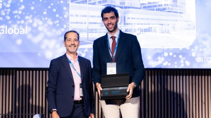 Dos hombres posando en el escenario el de la derecha con un premio en la mano
