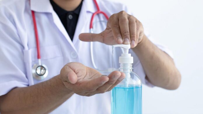 Médico con fonendoscopio aplicándose gel hidroalcohólico en sus dos manos