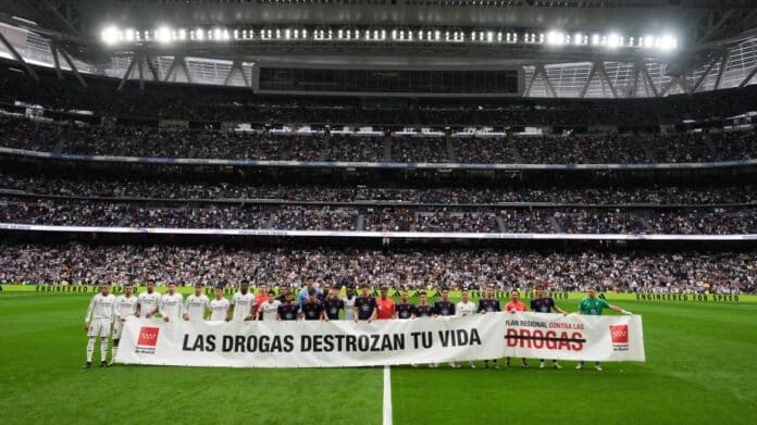 Jugadores de fútbol en el Santiago Bernabéu mostrando una pancarta del Plan Regional contra las Drogas 