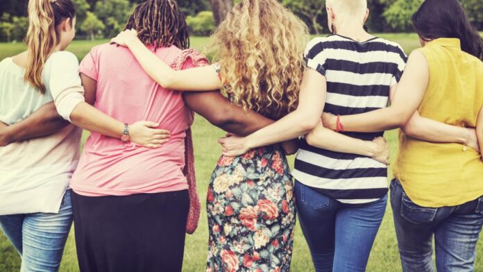 Varias mujeres de espaldas en línea abrazadas por la cintura