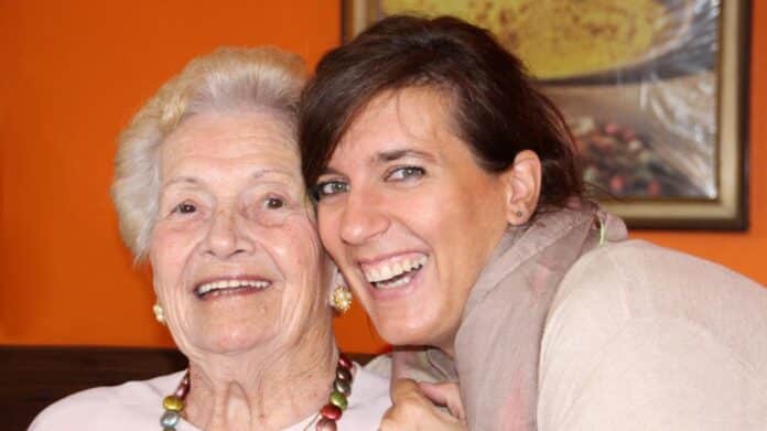 Mujeres, jóven y mayor, abrazadas sonriendo