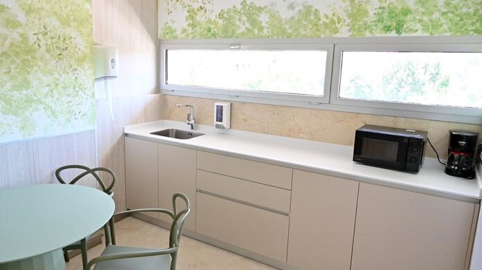 Sala equipada con un mesa y sillas y un office de cocina con nevera y microondas