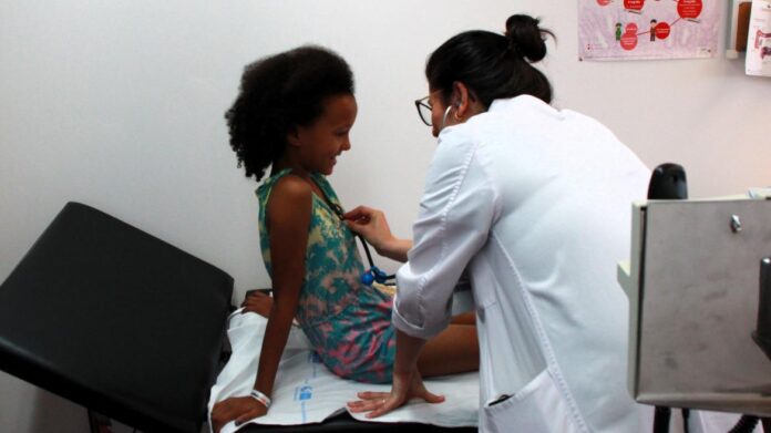 Médica comprueba estado de salud de una niña en una camilla