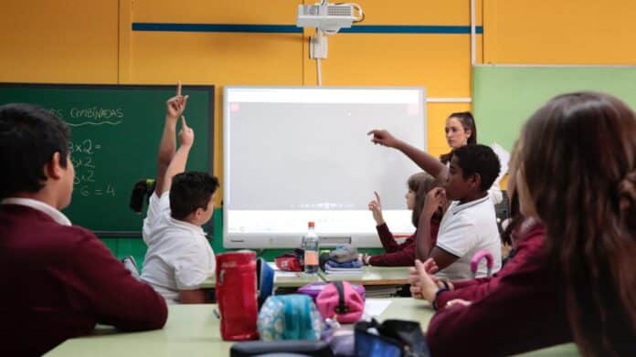 Estudiantes en clase preguntan a la profesora