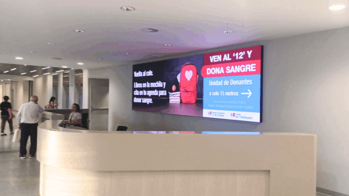 Pantalla grande en hall de hospital con una campaña
