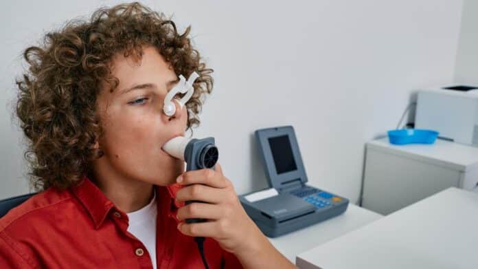 Niño rizado que realiza pruebas de función pulmonar y espirometría usando espirómetro 