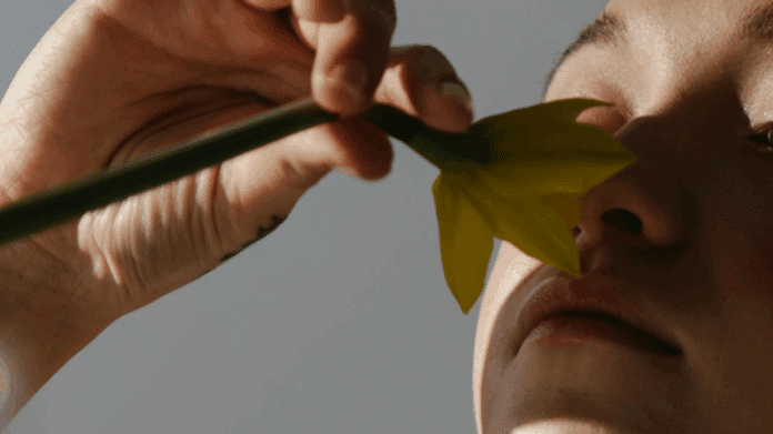 Imagen de una pernosa oliendo una flor