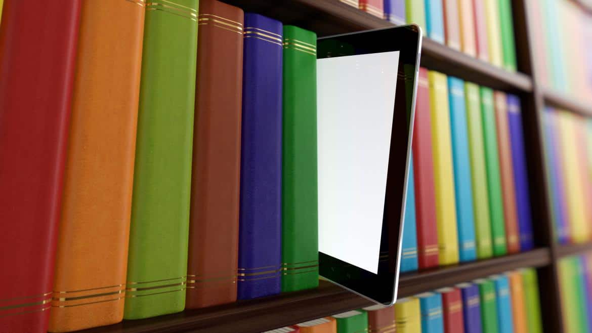 estantes con libros de colores y tableta electrónica sobresaliendo
